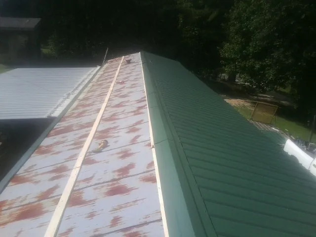 Old rusted panels beside newly installed green metal roofing — Wind Damage Roof Repair by Roofing Brothers in Dutch Flat
