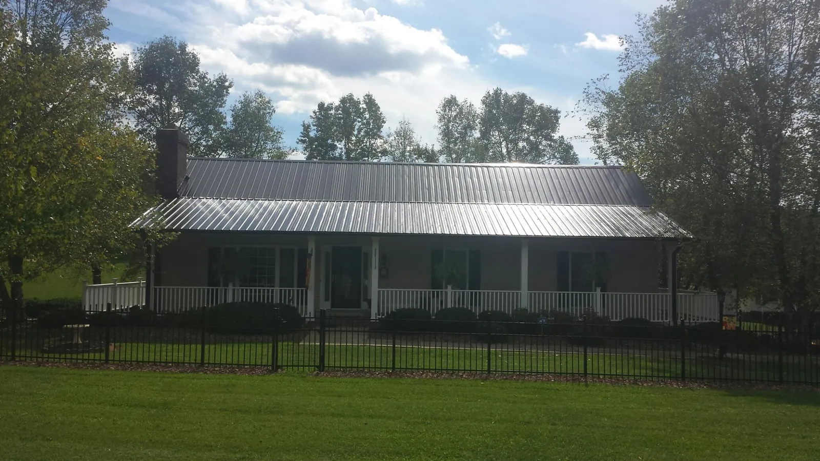 Gray metal roof on a brick ranch with a full width front porch — Gutter Guard Installation work by our crew in Dutch Flat