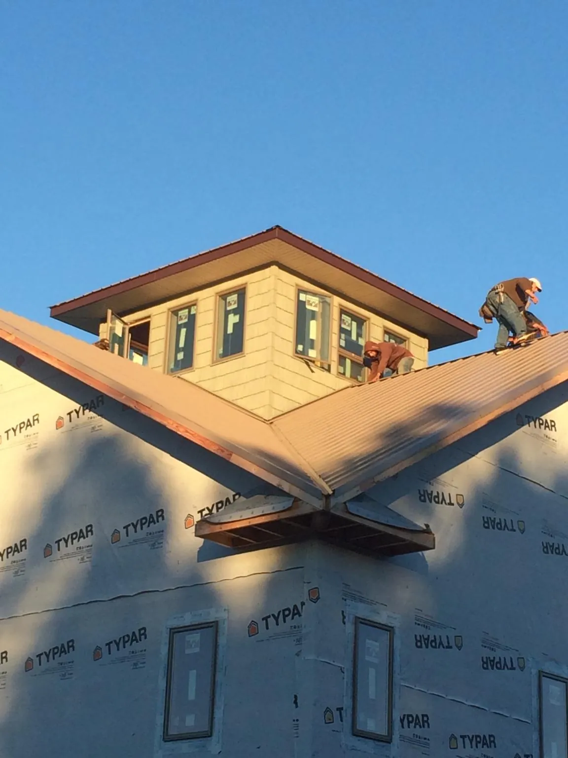 Roofers working around a rooftop cupola on a new metal roof at sunset — Roof Waterproofing in Dutch Flat by Roofing Brothers